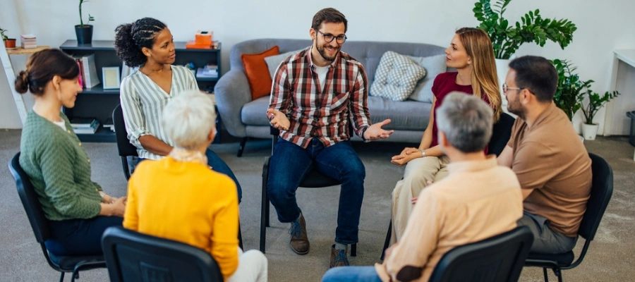 Image of men and women in a group with man holding out hands smiling - Alcoholics Anonymous meetings in Idaho