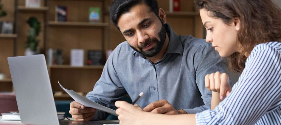 Image of work associates comparing notes by a computer -Job and education skills for recovering addicts