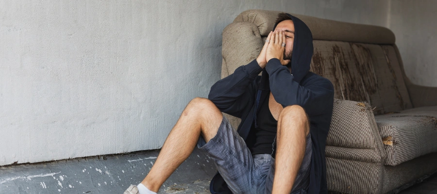 Image of a man sitting on the floor in despair with hands on his face - Warning Signs of Synthetic Marijuana Abuse