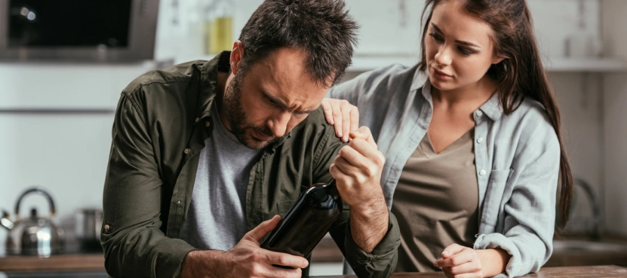 Image of a woman comforting husband sitting in despair, trying to encourage him to seek help