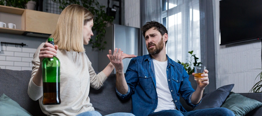 Image of a woman, holding a bottle of whiskey in her hand, trying to stop her husband from drinking alcohol, symbolizing setting boundaries and avoiding codependency
