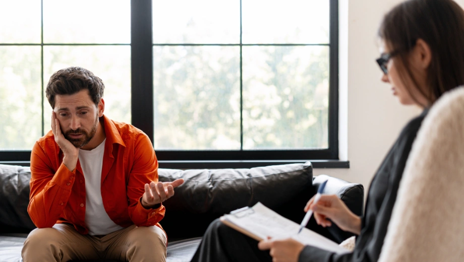 Image of a man sitting in Cognitive Processing Therapy with a female therapist - Cognitive Processing Therapy Worksheets to Support Recovery - Icarus Wellness and Recovery