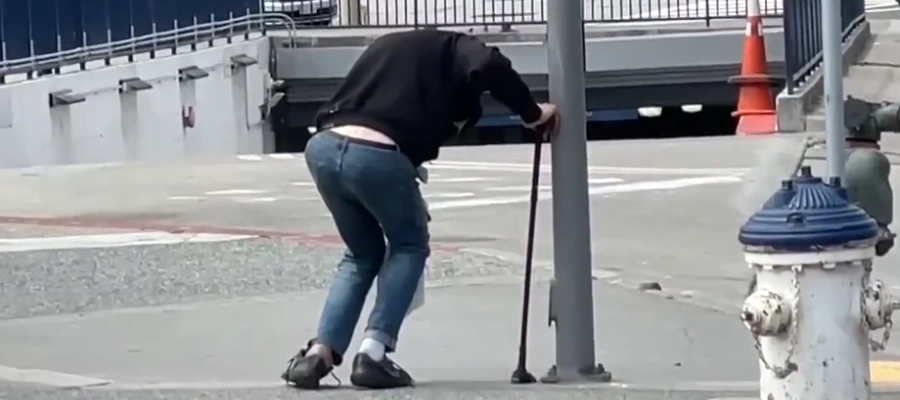 Image of a man slumped forward with fentanyl fold and trying to walking with a cane