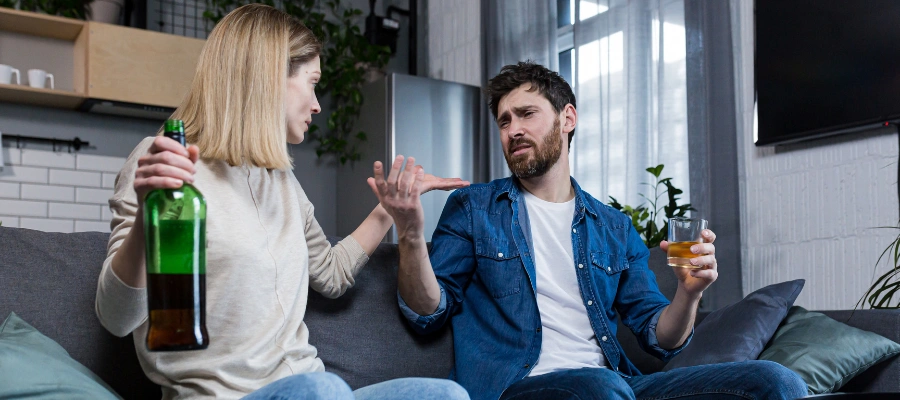 Image of a wife taking an alcohol bottle from her husband, showing concern and intervention as part of addressing potential alcohol misuse