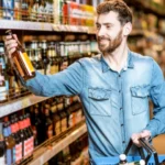 Image of a man in a store holding a bottle of alcohol in his hand - What Time Can You Buy Alcohol in Idaho - Icarus Wellness and Recovery