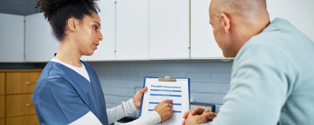Image of a calm conversation between an admissions coordinator and a client reviewing insurance paperwork