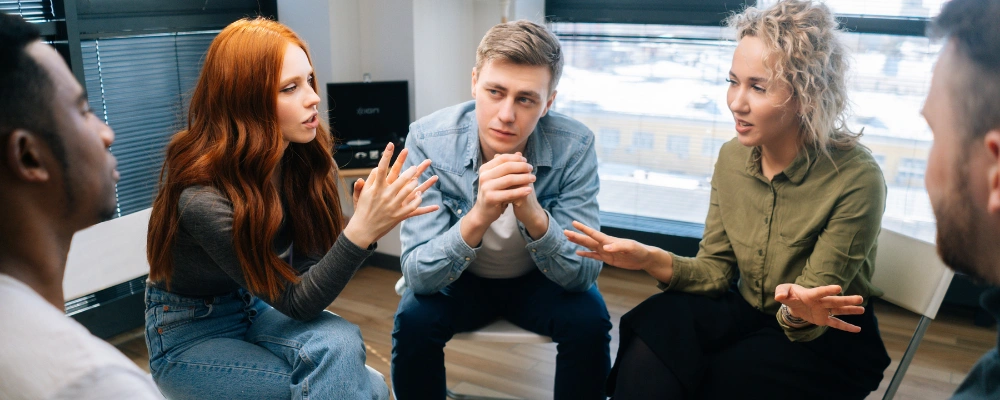 Image of a small group of adults participating in an outpatient group therapy session with a counselor