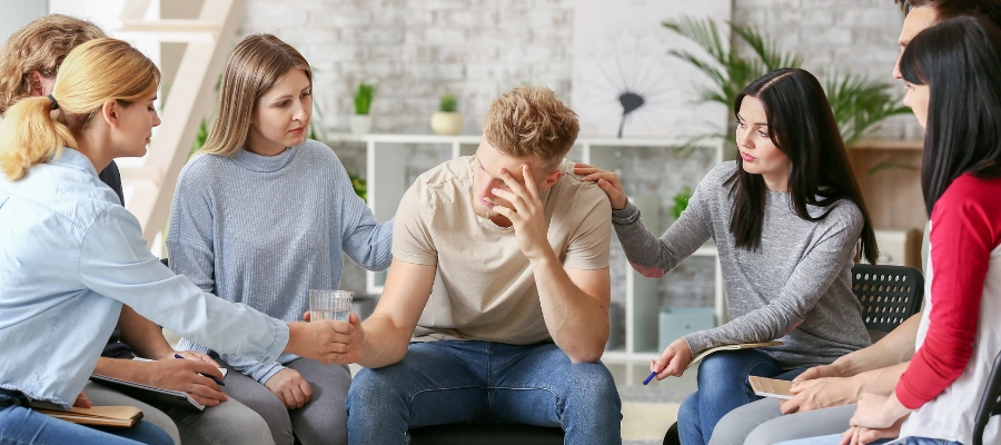 Image of a supportive group therapy session in rehab helping a man cope with urges to leave treatment early