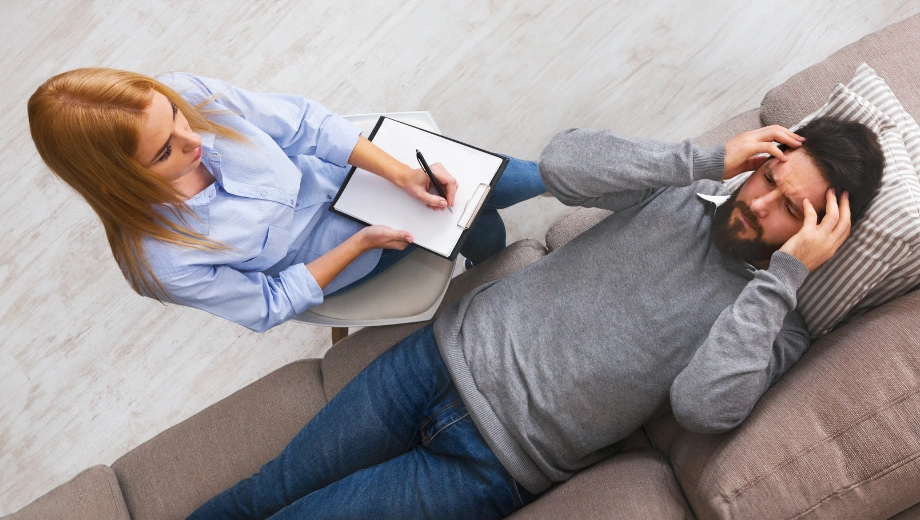Image of a counselor talking to a male patient, lying on a sofa - REBT Therapy Worksheets and PDF - Icarus Wellness and Recovery