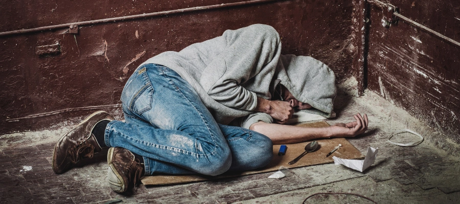 Image of man lying on the ground, struggling with substance use, representing drug addiction