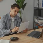 Image of a man sitting at a desk with his laptop, reviewing an insurance application -Does St. Luke's Health Plan Cover Addiction Treatment in Idaho - Icarus Wellness and Recovery