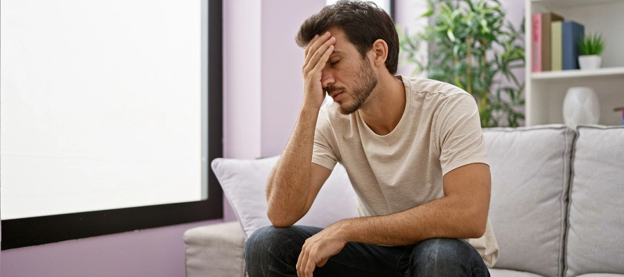 Image of a man sitting alone at home looking distressed representing the addictive effects of pseudo kratom tablet use