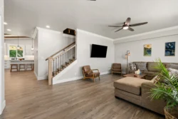 Open-plan living room with staircase and ceiling fan in residential rehab facility