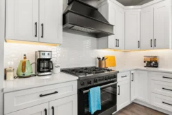 Modern white kitchen with oven and black range hood in Icarus Idaho facility